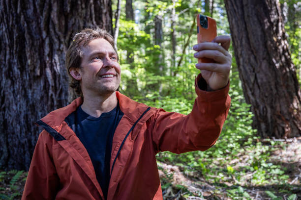 istock A man is taking a picture of a large tree with a camera phone. 2179862214