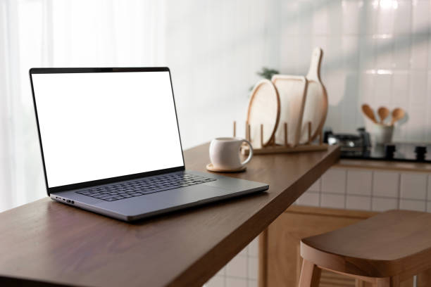 istock Open laptop with blank screen on a wooden desk in a kitchen room home office 2179864247