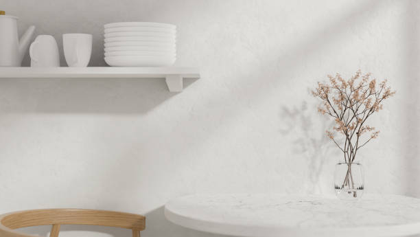 istock A round white dining table with a vase, a wooden armchair, and a wall shelf displaying kitchenware. 2179879698