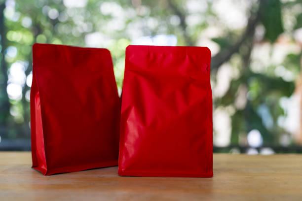 Roasted coffee in red zipper bag against nature background.