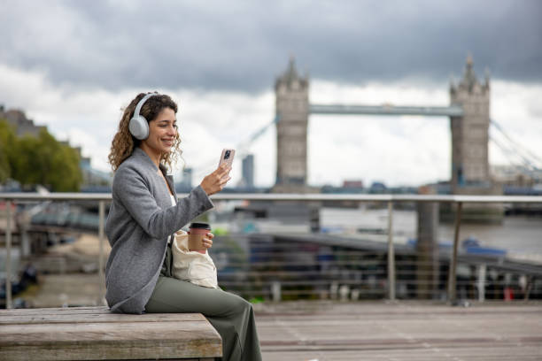 istock Tourist in London using her cell phone while drinking a cup of coffee on the go 2179891825