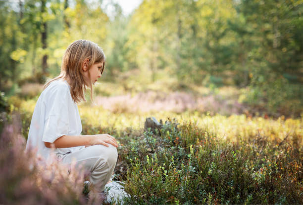 istock A young child sits peacefully among wildflowers in a serene forest during a bright summer afternoon 2179900082