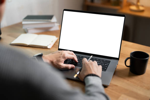istock Close-up image of a man working on laptop computer at a table, typing on the laptop keyboard. the laptop with a white screen mockup 2179907928