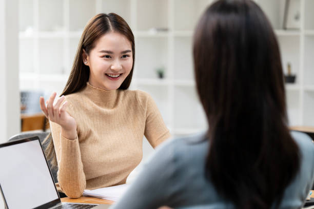 istock Two cute asian business women sitting and talking about planning and analyzing documents in workplace office 2179908489