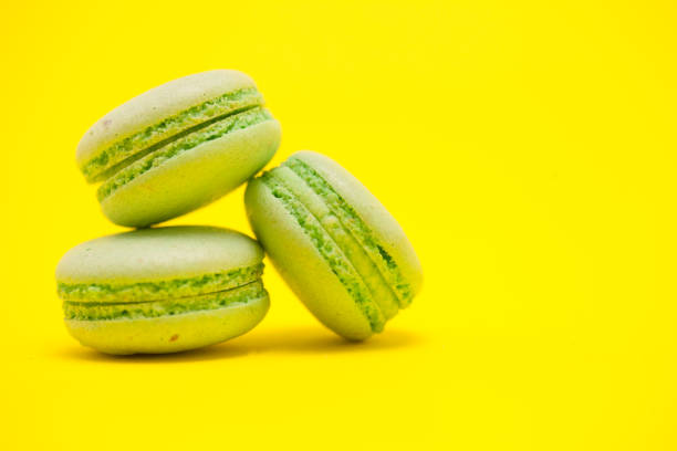 Delicate sweet green macaroons over yellow background. Sweet biscuits