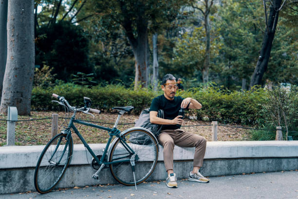istock Businessman with a bicycle taking a break in a city park 2179913585