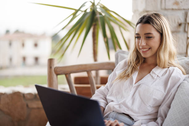 istock Young female digital nomad working on laptop on sunny balcony during vacation 2179918126