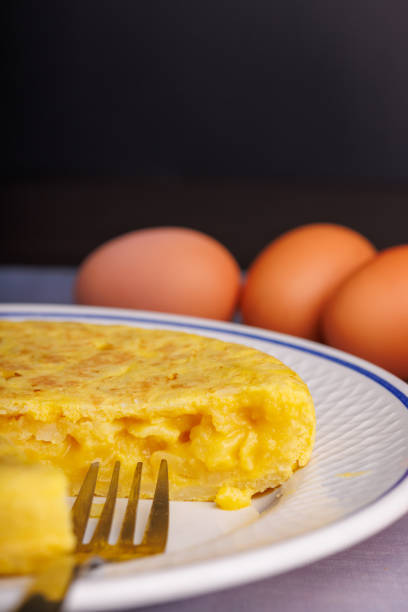 Spanish potatoe omelet in dish over wood surface and black background.