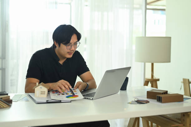 istock Young man working on a design project reviewing color chart and using laptop at desk 2179924775