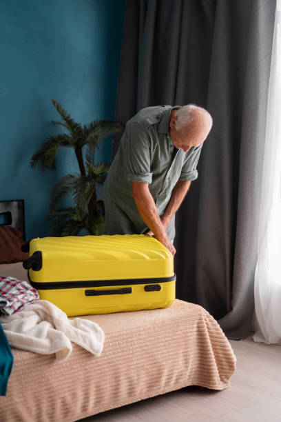 istock Retired elderly man packing suitcase at home for journey 2179931343