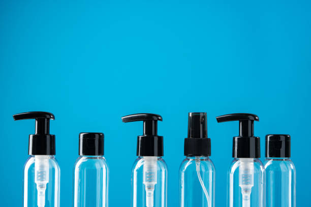 Clear plastic bottles with black caps arranged on a white surface against a bright blue background