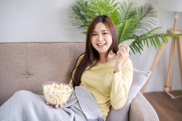 istock Asian woman Watching smart TV and using remote controller Hand holding television audio remote control at home with the remote control television 2179937674