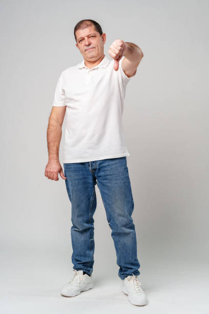 istock A middle-aged man expressing disapproval with a thumbs-down gesture i 2179941230