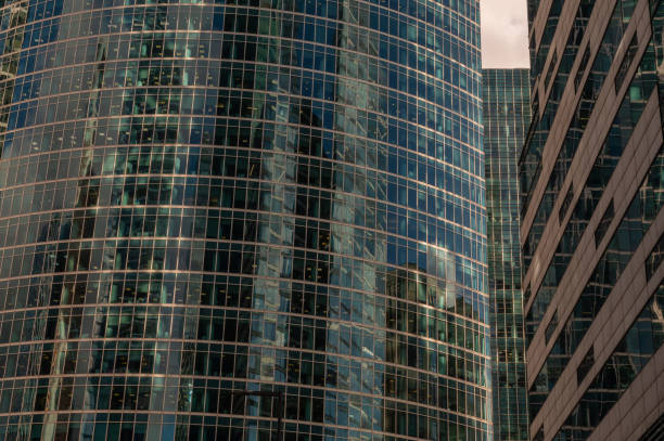 Angled view of modern skyscrapers in business district against blue sky. Looking Up high-rise office buildings. Evening time, sunset. Orange, yellow and gold shades of color.
