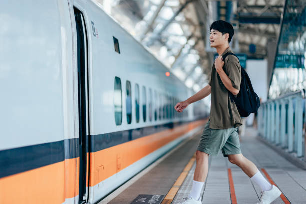 istock A male backpacker drags her suitcase into the train carriage, smiling with excitement as she looks forward to her trip. 2179944723