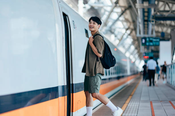 A male backpacker drags her suitcase into the train carriage, smiling with excitement as she looks forward to her trip.