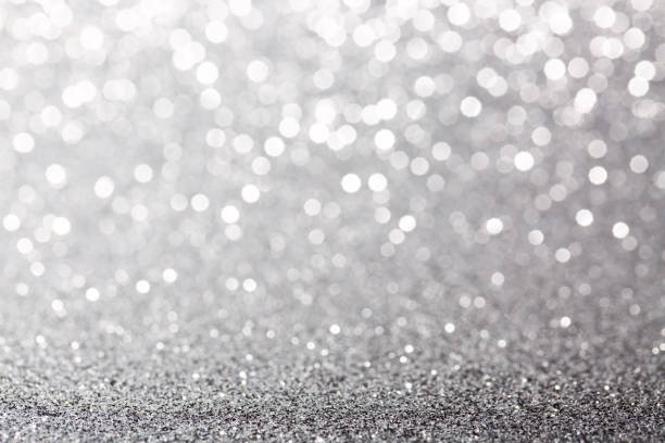 Metallic foil background. Shiny metal silver foil texture abstract defocused background. Sparkle glitter texture with bokeh lights. Holiday Christmas image.