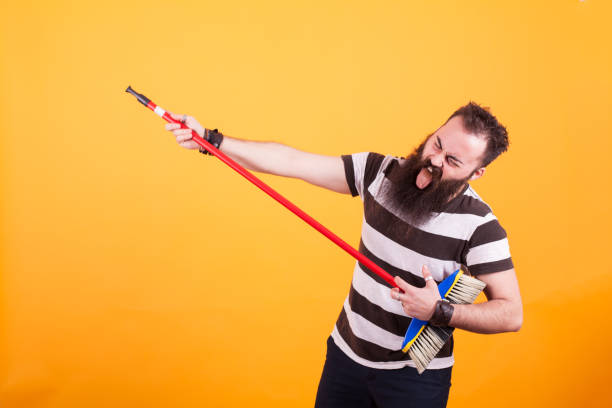 istock Funny bearded rockstar playing virtual guitar with broom 2179946355