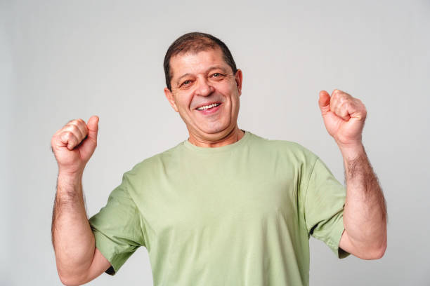 istock Happy elderly man celebrating a victory with joyful gestures in a light-colored setting 2179946428