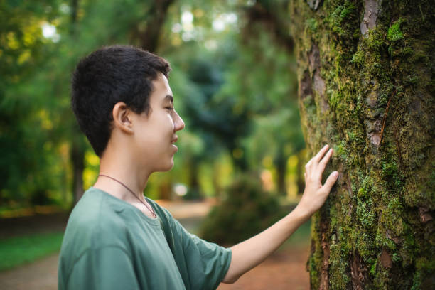 istock Teenage boy touching a tree, forest bathing and connection with nature concept 2179946626