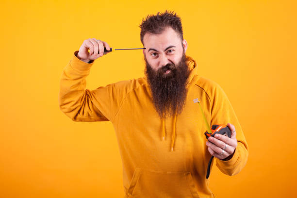 istock Bearded architech holding roulette and screwdriver over yellow background 2179947026