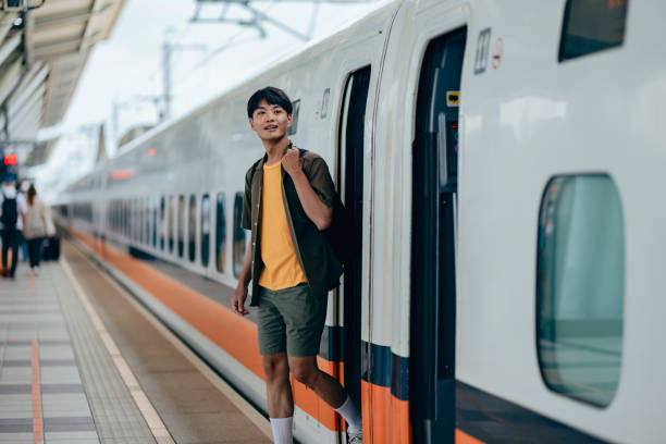 istock A male backpacker drags her suitcase into the train carriage, smiling with excitement as she looks forward to her trip. 2179947044
