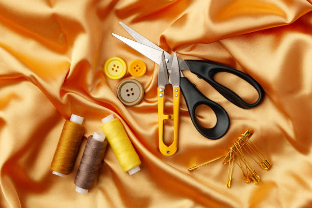 istock Crafting essentials arranged on golden satin fabric with sewing tools and colorful buttons scattered around 2179947396