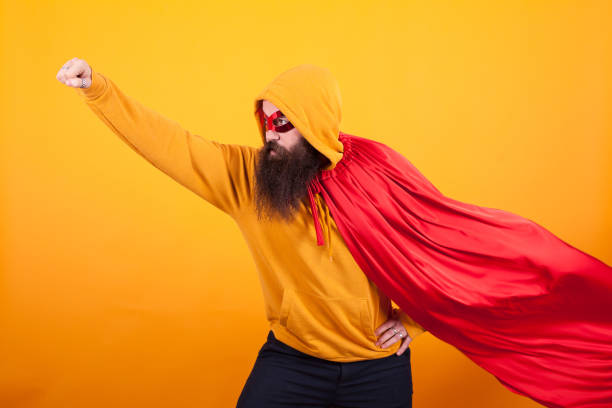 Superhero with red cape and mask flying away in studio over yellow background., Brave man. Handsome.