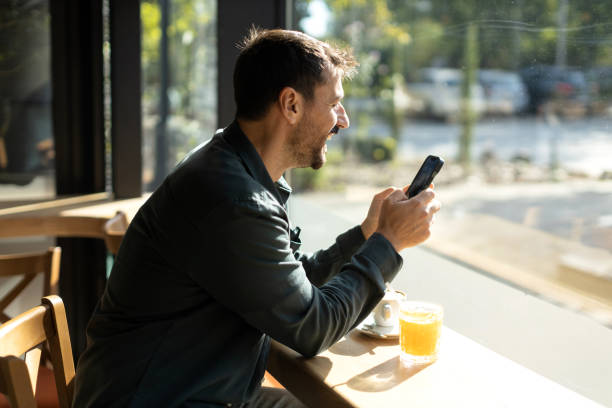 istock Young male sitting in the cafe and using smart phone 2179948374