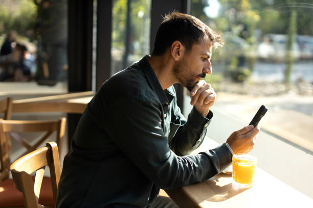 istock Young male sitting in the cafe and using smart phone 2179948411