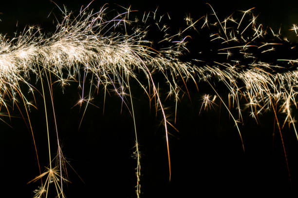 Line of christmas sparklers light trail on black background.