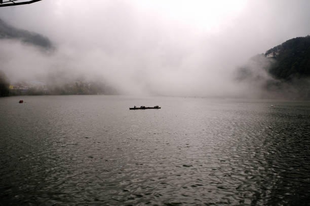 A serene lake shrouded in mist, with a boat gently floating on the water.
