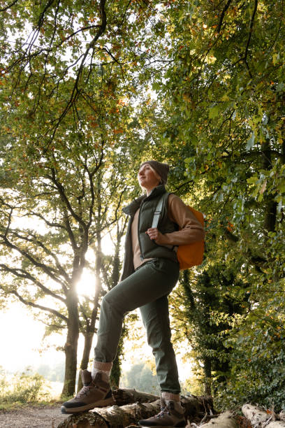 Woman with backpack walking in forest at autumn