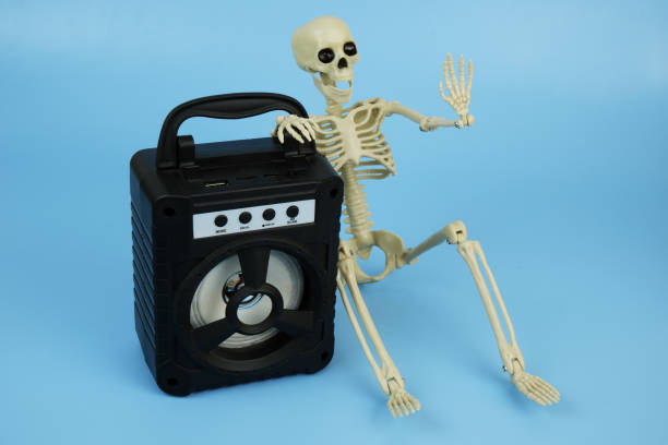 istock Death or human skeleton sitting with black audio speaker on blue background. 2179955878