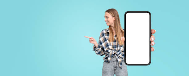 istock Woman pointing at smartphone with blank screen on turquoise background. 2179956960