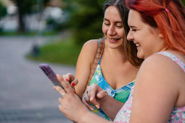 istock Two Female Friends Using Smart Phone In The Park 2179960211