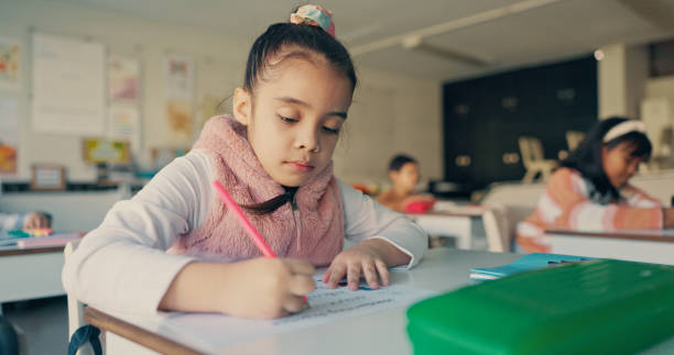 istock Girl, child and writing test in classroom for education, learning and assessment for progress at academy. School kids, exam or quiz for development, scholarship or problem solving with question paper 2179961207
