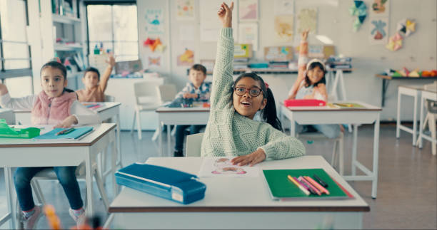 istock Girl, child and happy with raised hand at school for question, answer and smile with solution for quiz. Kids, excited and group for problem solving, learning and assessment for education in classroom 2179961212