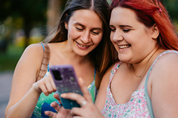 istock Two Female Friends Using Smart Phone In The Park 2179961214