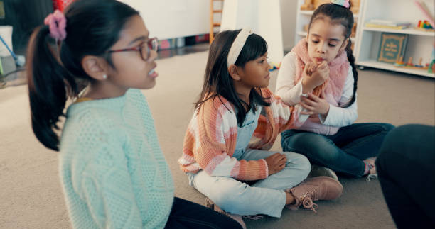 istock Students, girl and children on floor in classroom for reading group, learning and academic development. Kindergarten, kids and learner on ground at school for study activity, education or scholarship 2179961250