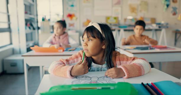 istock School, thinking and girl in kids classroom with notebook, growth and creative development in education. Study, learning and student at desk with writing, drawing and art stationery for children 2179961297