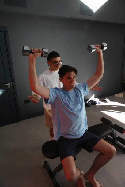 istock Person assisting man exercising with dumbbells 2179967911