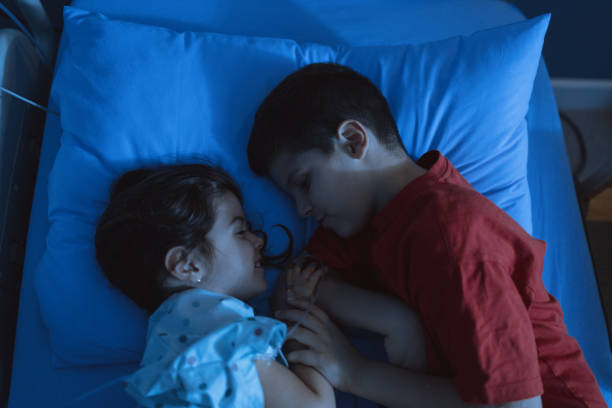 Lovely brother and sister sleeping in the hospital bed at night