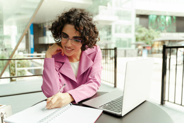 istock Businesswoman taking notes while working on laptop at cafe 2179976710