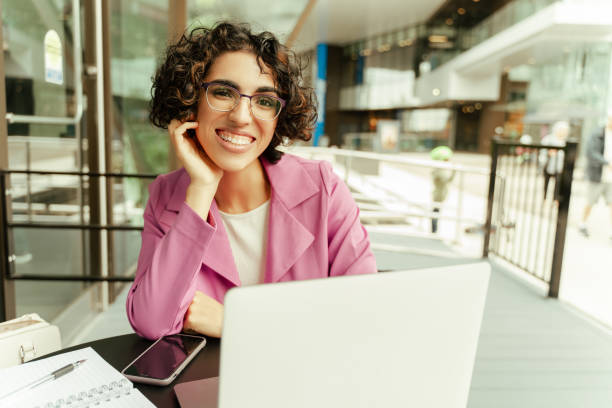 Beautiful businesswoman smiling while working on laptop at cafe