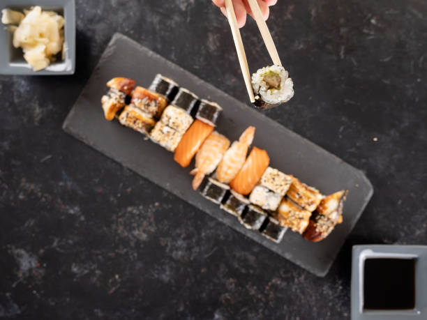 istock Top view hands with chopsticks picking a sushi roll 2179986967