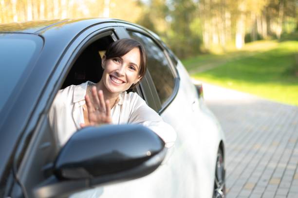 istock Woman waving from car window on a sunny day. 2179987572