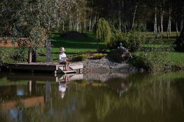 istock Boy fishing on a dock by a pond 2179987770