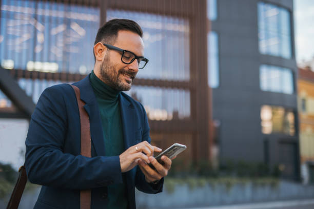 istock A handsome, smiling, well-dressed middle-aged man is going to work and holding a briefcase in his hand, with a modern building in the background. The photograph captures the fast-paced lifestyle and a business moment 2179989796