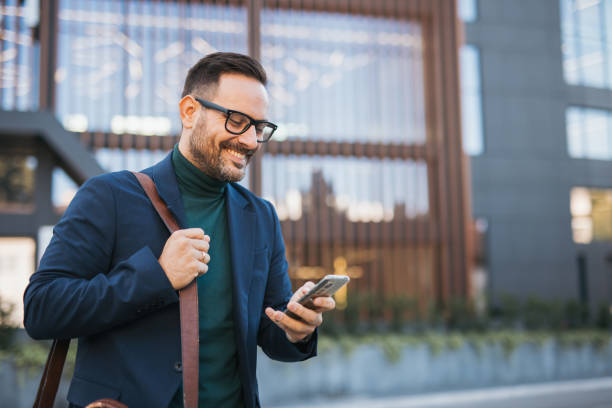 istock A handsome, smiling, well-dressed middle-aged man is going to work and holding a briefcase in his hand, with a modern building in the background. The photograph captures the fast-paced lifestyle and a business moment 2179989810